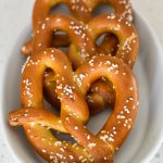 Three soft pretzels with coarse salt on top of them that ave been browned and cooked in an air fryer.