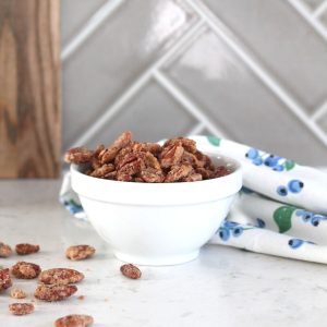 air fryer candied pecans in white bowl next to blueberry print tea towel
