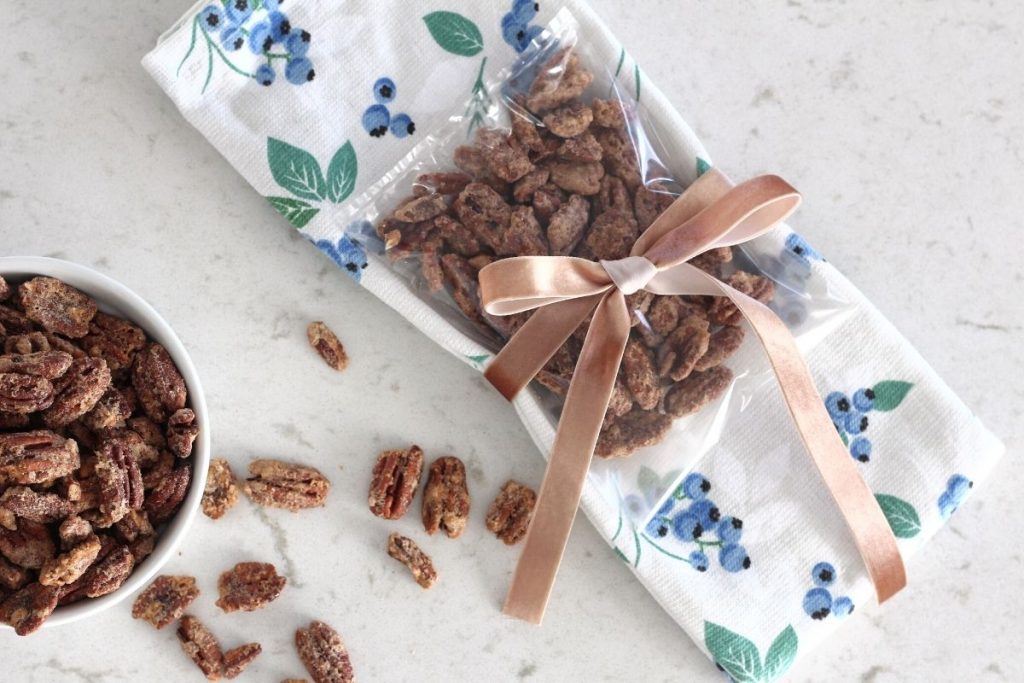 Easy air fryer candied pecans styled as gift in clear bag, tied to blueberry print dish towel