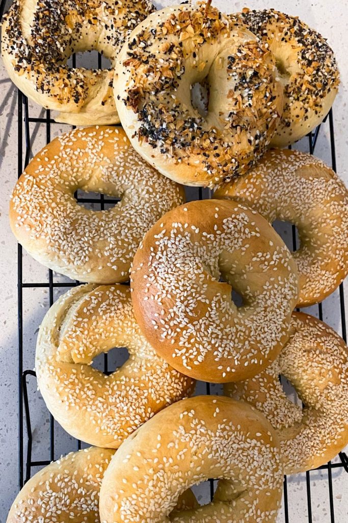 Several everything and sesame bagels on a cooling rack.