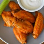 Buffalo wings on a plate with celery and ranch dressing.