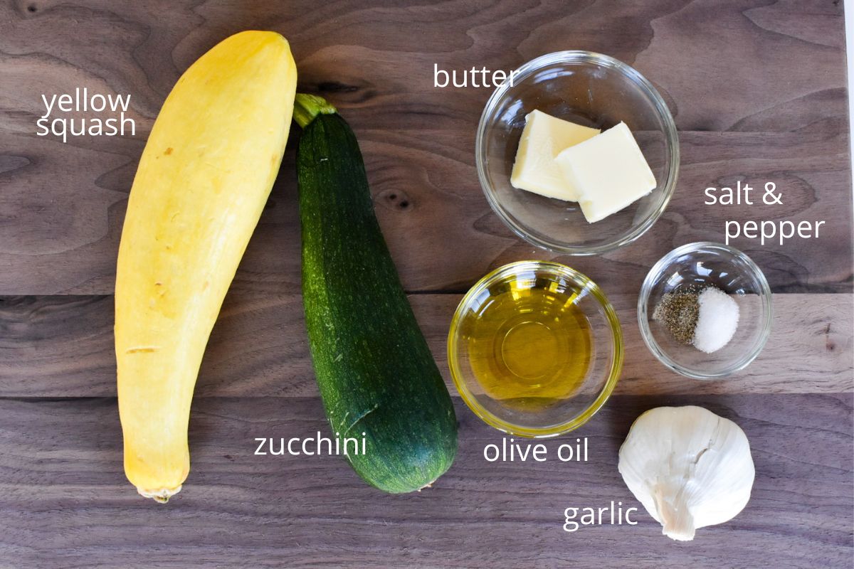 The ingredients to make sautéed zucchini and yellow squash on a wood board.