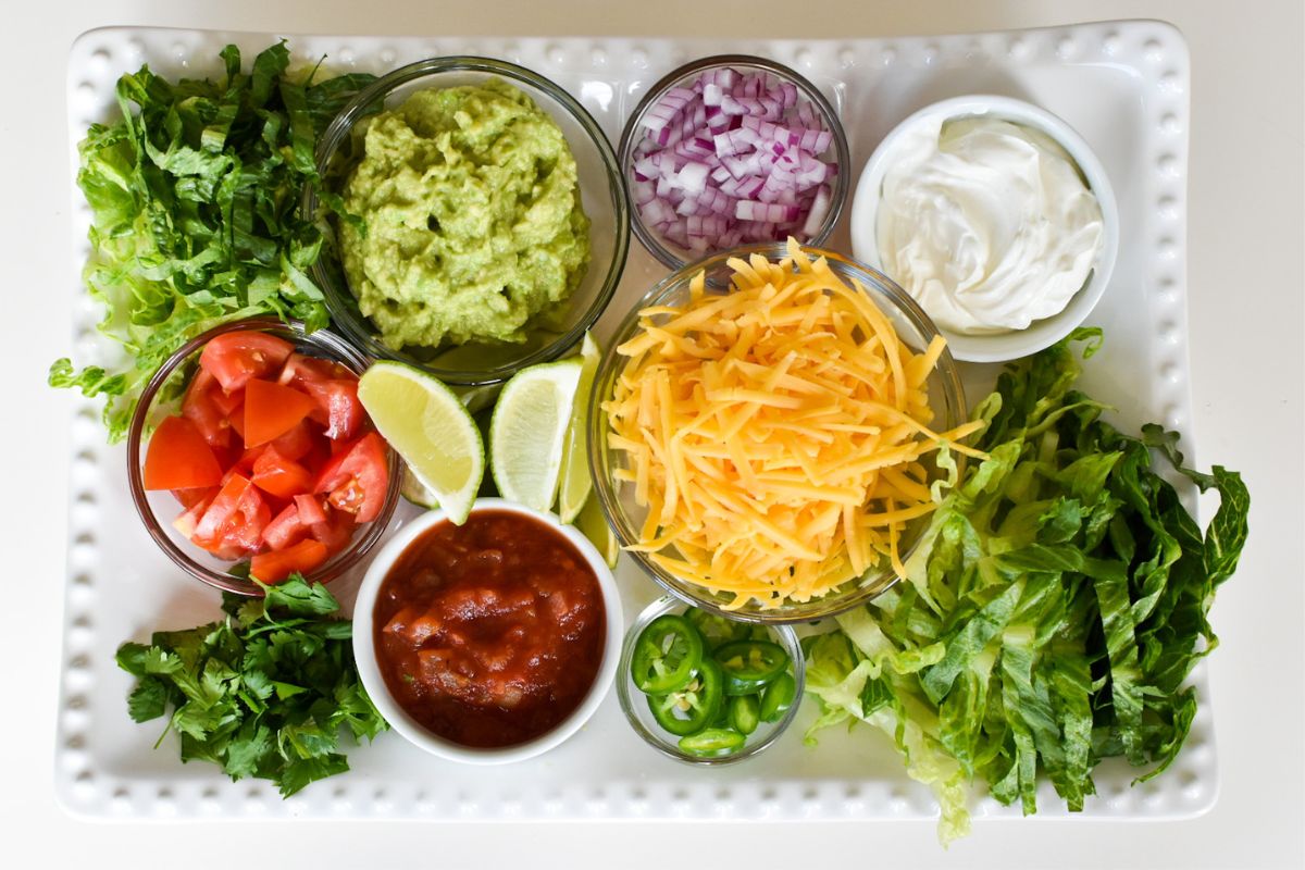 Toppings for tacos on a large white platter.