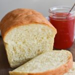 Sliced fluffy sandwich bread with a jar of jam next to it.