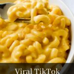 A fork scooping up creamy oven baked mac and cheese in a bowl with text: Viral TikTok mac and cheese.