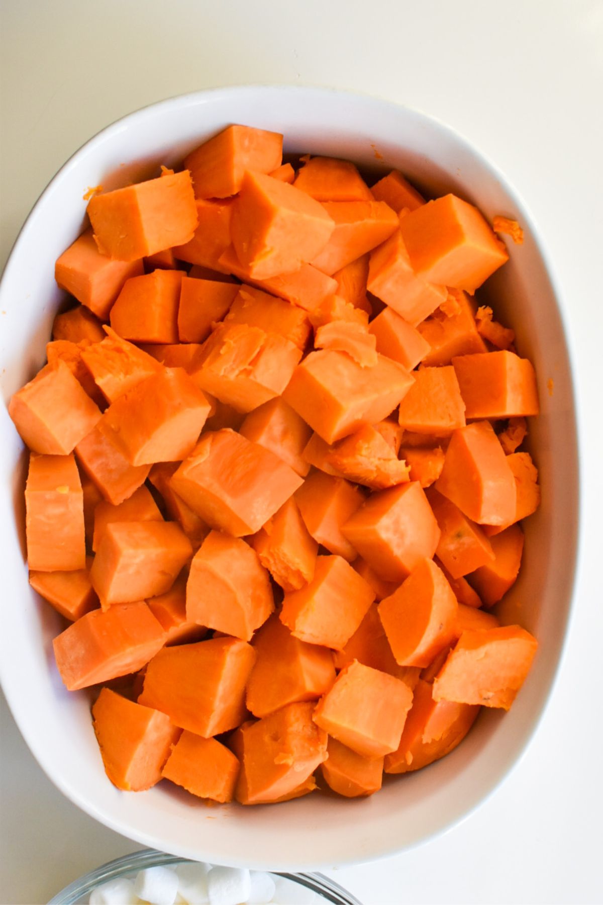Cubed sweet potatoes in a white casserole dish.