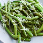 Cooked green beans with shredded fresh parmesan on top.