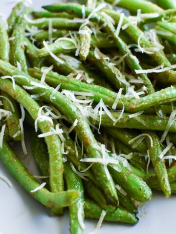 Cooked green beans with shredded fresh parmesan on top.