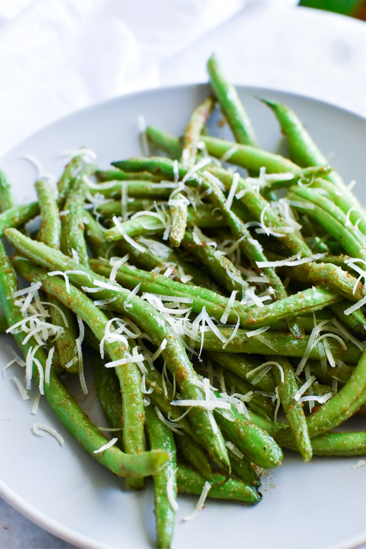 Cooked green beans with shredded fresh parmesan on top.