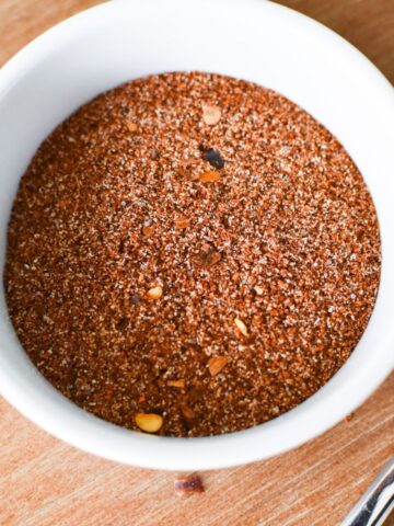 Chili seasoning in a small white bowl with a spoon next to it.
