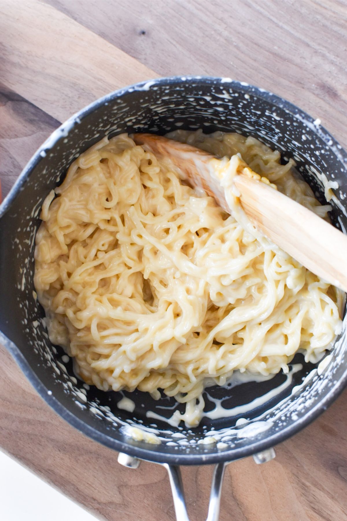 Cheesy ramen being stirred in a pot to allow the cheese to melt.