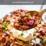 A spoon holding a bite of chili over a bowl of chili with the text: Texas Roadhouse chili recipe.