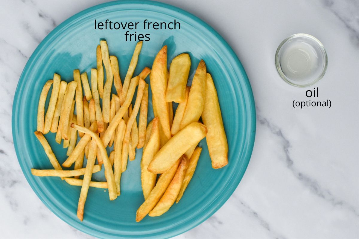 Leftover french fries on a teal plate with a small condiment cup of oil next to it.