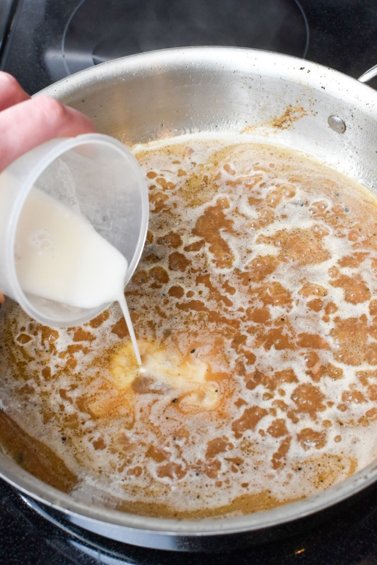 Adding a flour and water mixture to the pan to thicken the gravy.