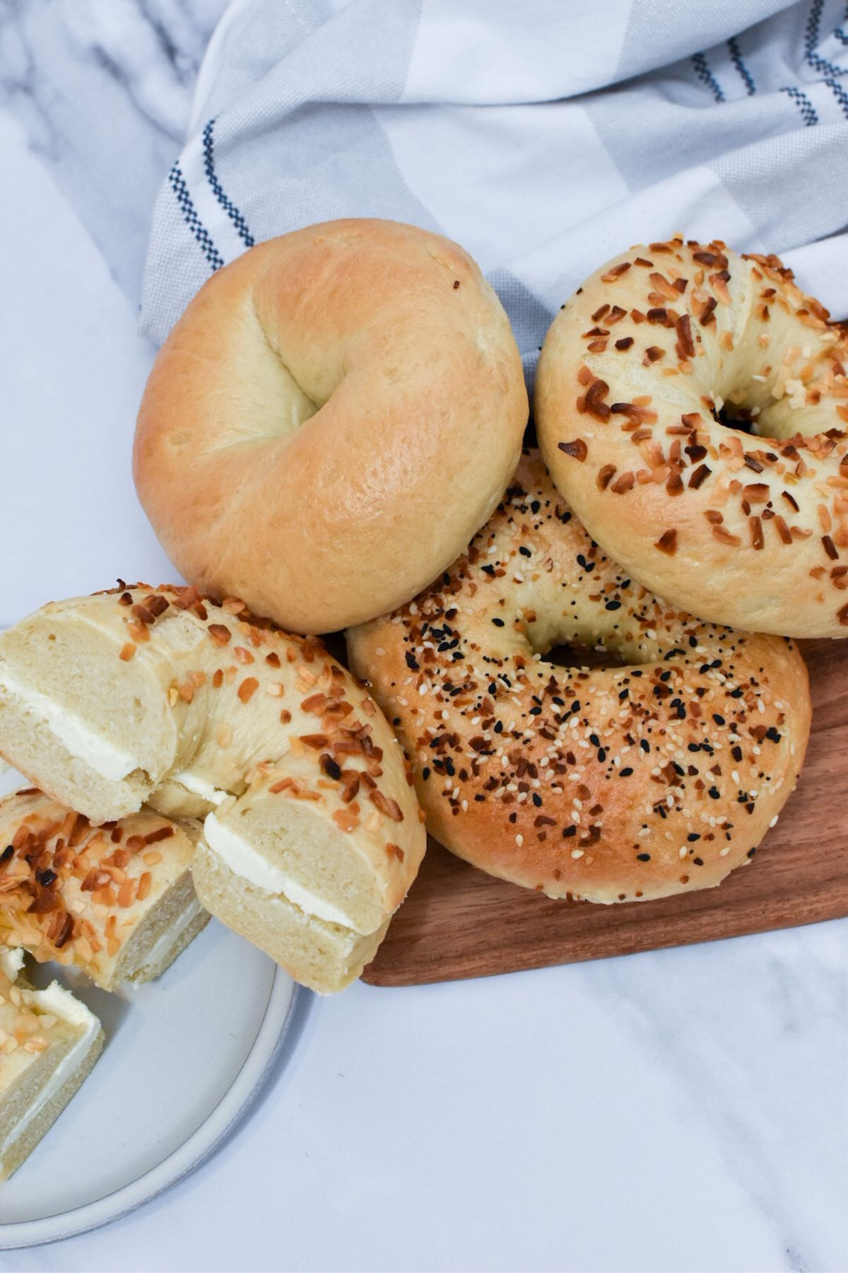 An onion bagel with cream cheese and a stack of bagels next to it.