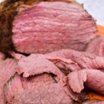 Thin slices of eye of round roast with the remaining roast behind it.