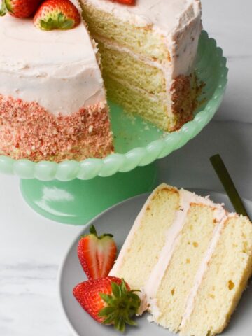 Strawberry crunch cake with a slice on a plate with a couple of strawberries next to it.