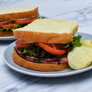 A sandwich with ham, lettuce, tomato and onion on homemade Italian sandwich bread.