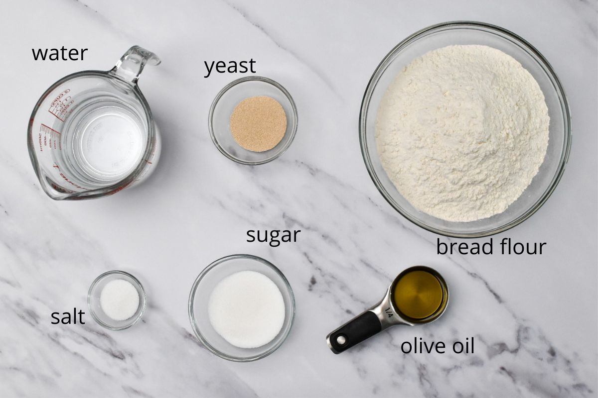 The ingredients for Italian sandwich bread in bowls on a counter.