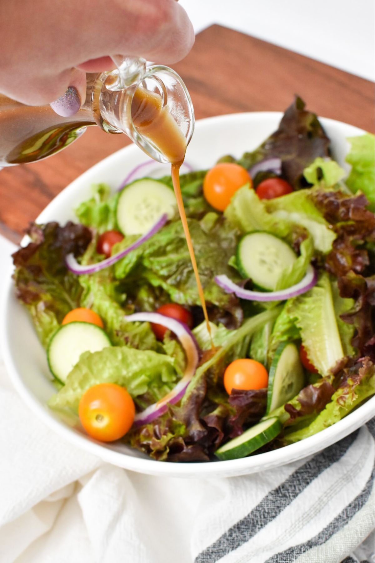Balsamic vinegar and olive oil dressing being poured on top of a salad.