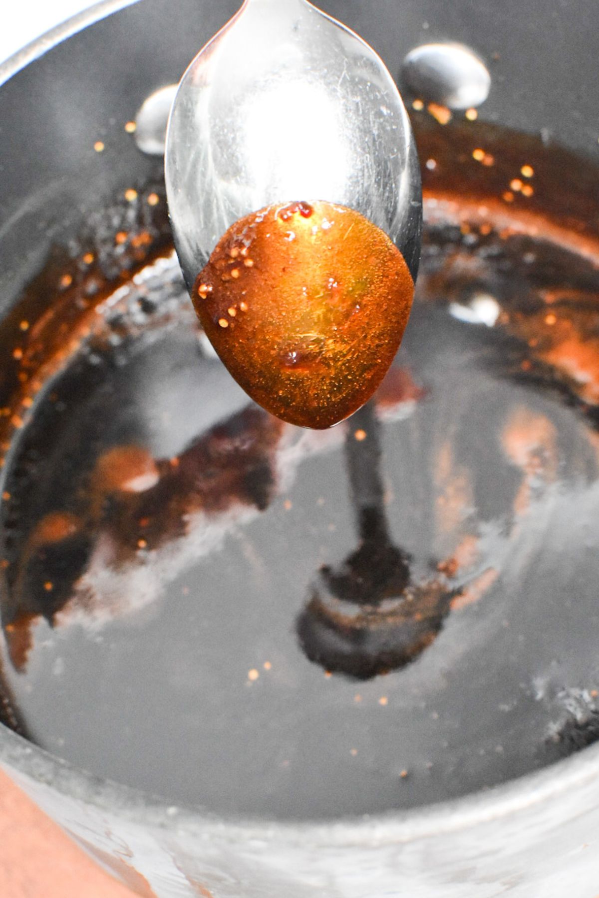 A metal spoon with fig glaze coating it.