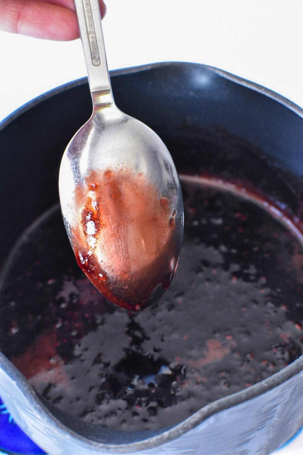 Raspberry glaze coating the back of a metal spoon.