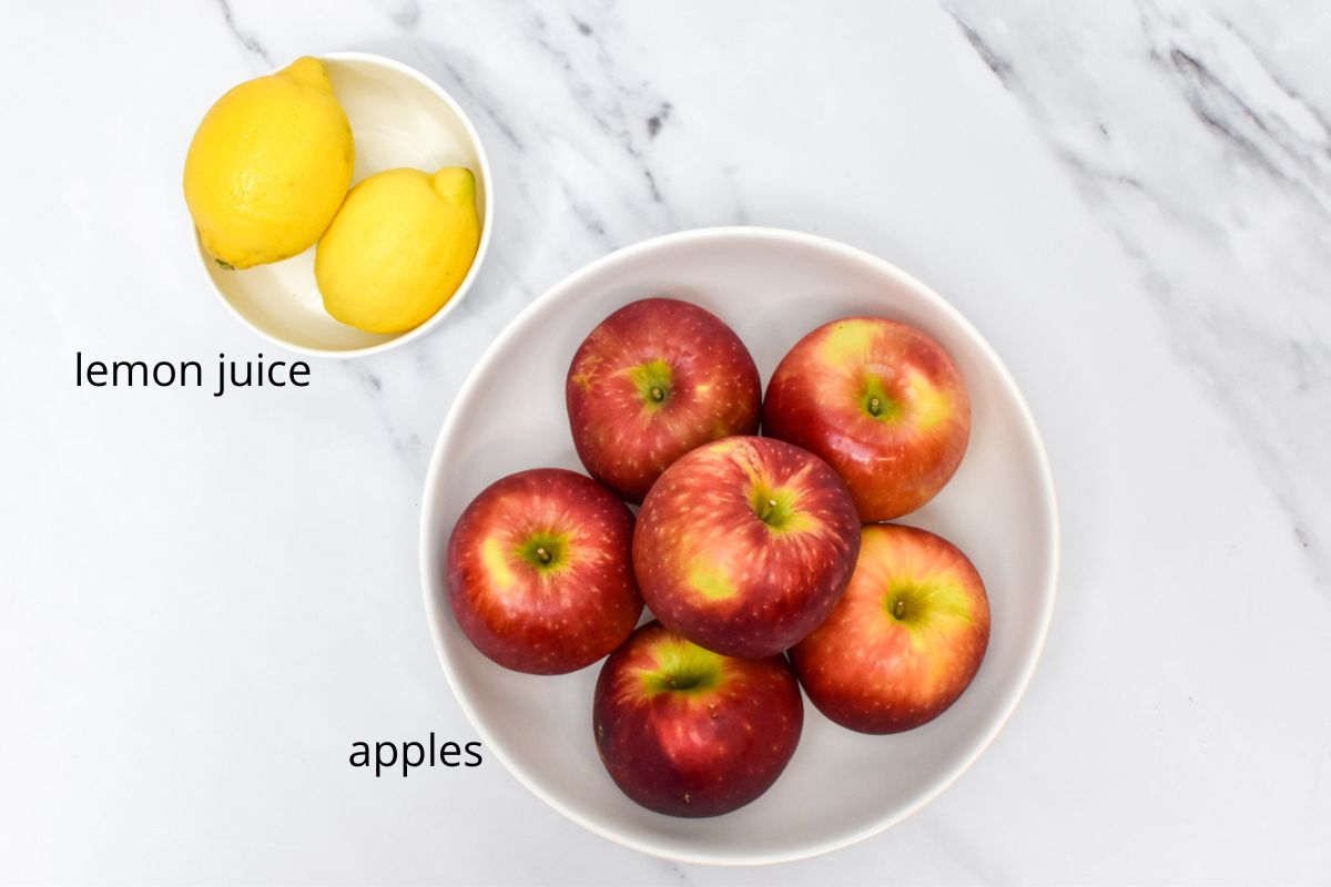 A bowl of apples and a small bowl of two lemons.
