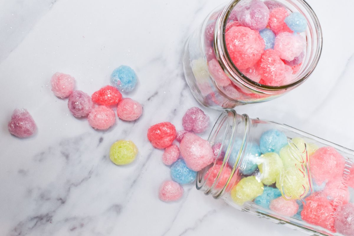 Two glass jars of freeze dried Jolly Ranchers with one turned on its side with freeze dried Jolly Ranchers spilling out.