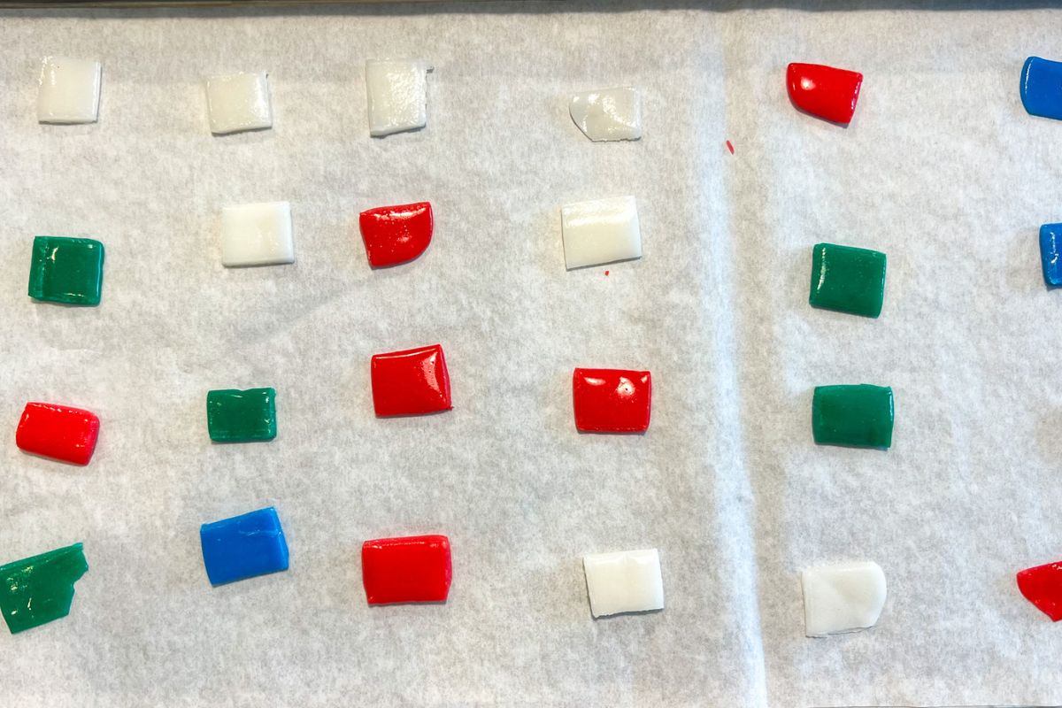 Small square pieces of Airheads on parchment paper lined freeze dryer trays.