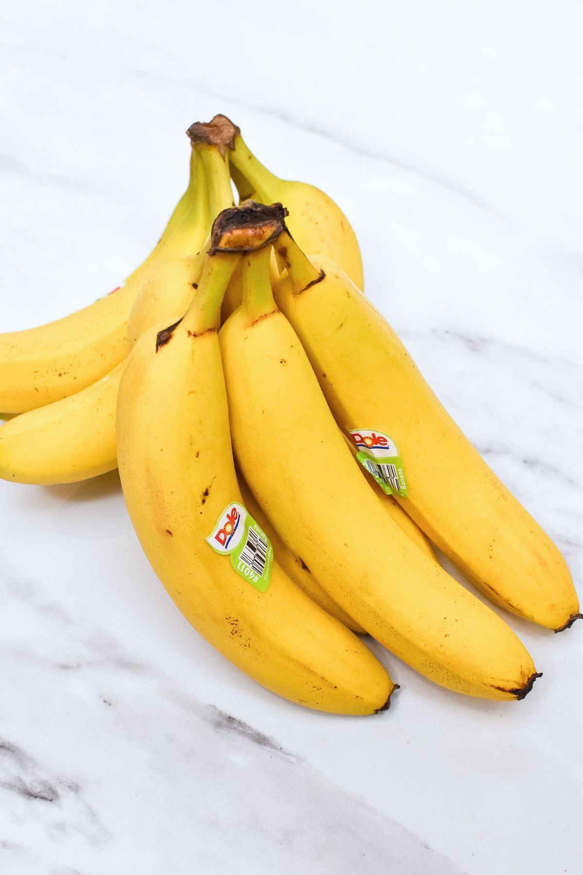 Two bunches of bananas on a countertop.