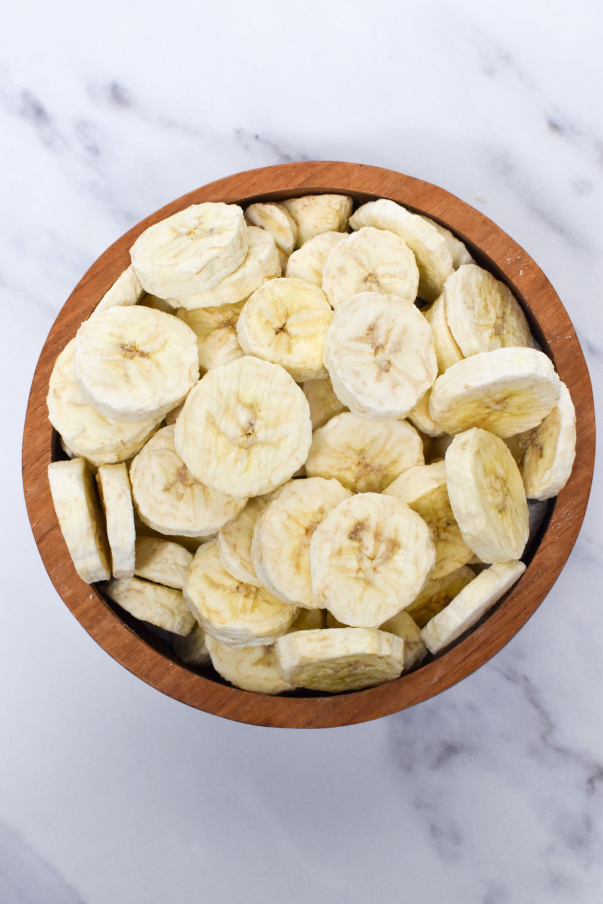 A wooden bowl full of freeze dried bananas.